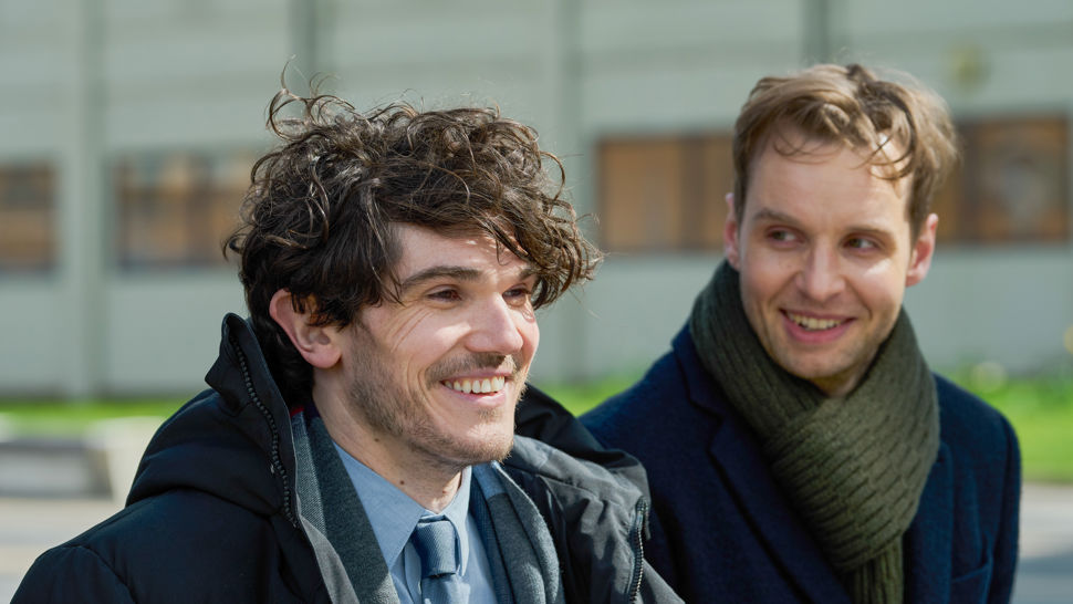 Two men share a smile while sitting outside