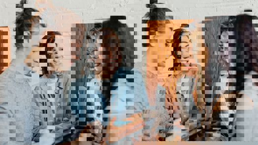 Group of young people standing with coffee around a laptop