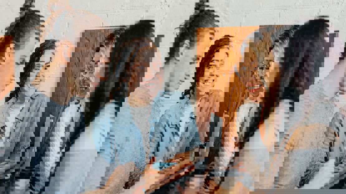 Group of young people standing with coffee around a laptop