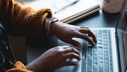 Close up of hands tapping on a laptop keyboard on a desk