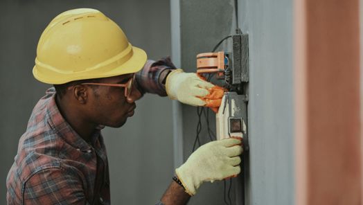An electrician rewiring a fuse board on a wall