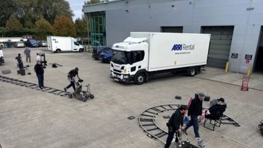A warehouse car park with several cars and vans parked and a team operating two dollies