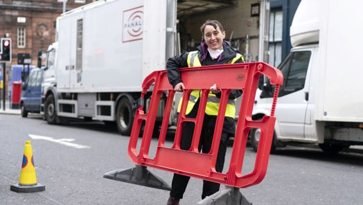 Assistant in high-visibility vest lifting portable fence