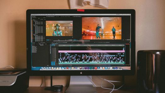A MacBook computer is sat on a table. The screen is opened a page of editing software.