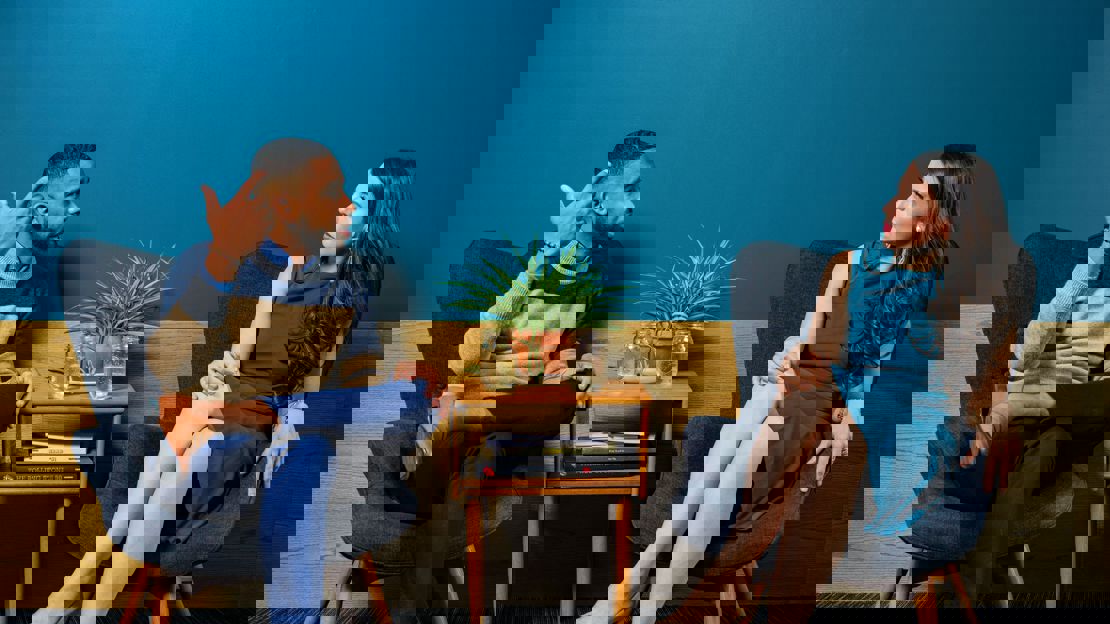 A young man and a young woman sat at a coffee table in conversation