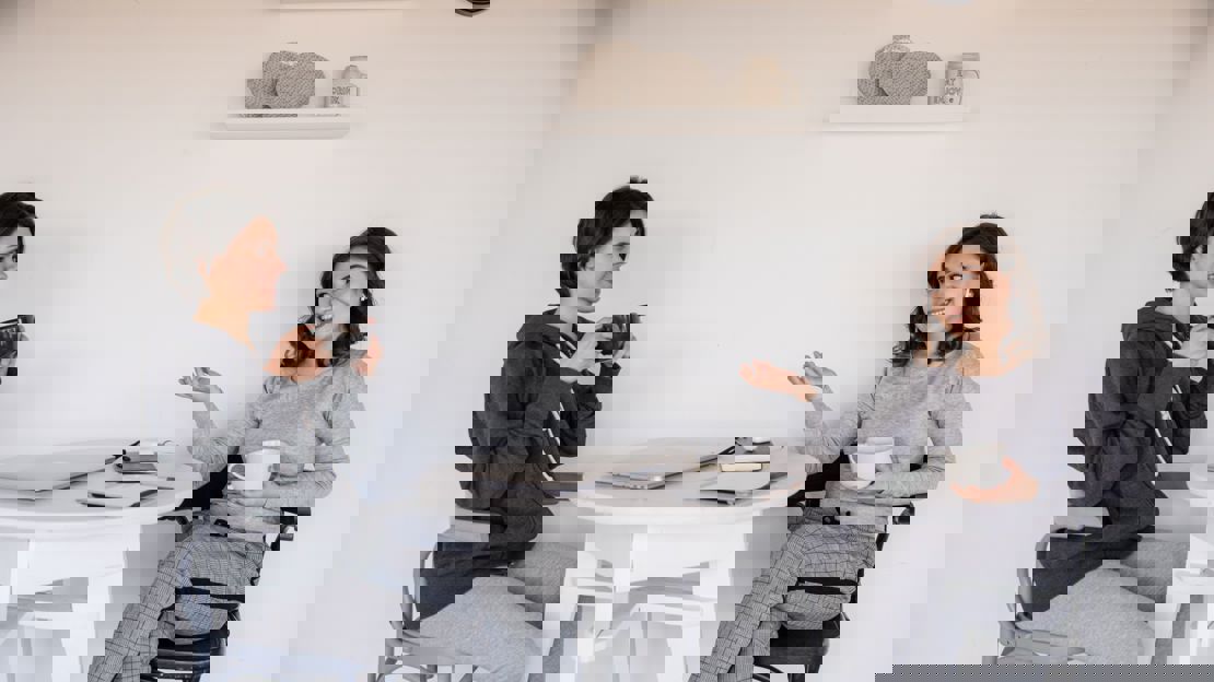 Two women sat at a table drinking coffee and chatting