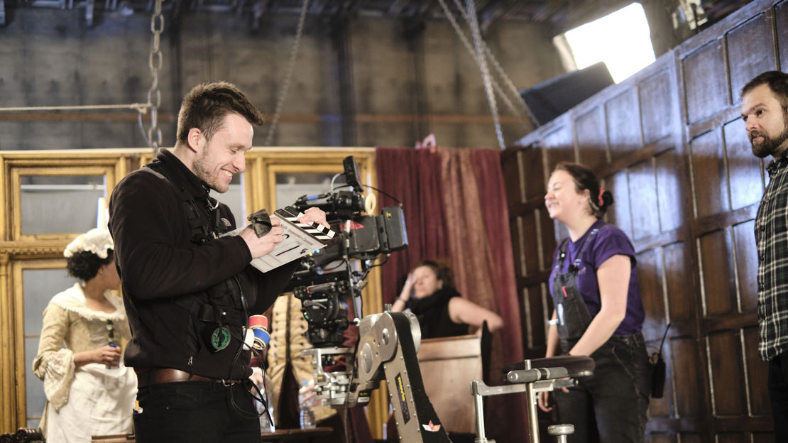 Behind the scenes image of cameraman and other crew on set of a period drama