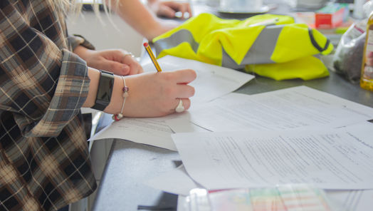 Close up of person signing document next to high vis jacket