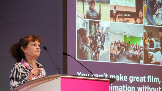 Emma Turner stands at a podium delivering a speech to an audience